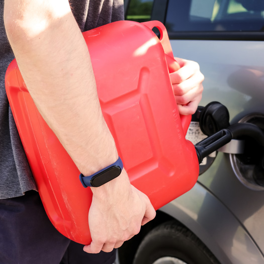 A red canister on the asphalt near the car